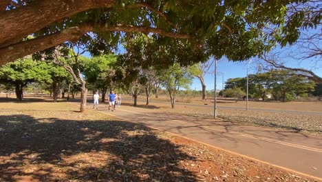 stable-shot-with-a-busy-footpath-next-to-an-equally-busy-bike-path-in-the-city-park-of-brasilia-on-a-summer-day