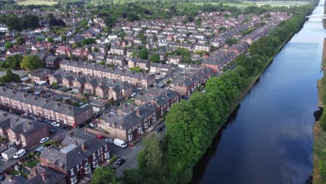 Aerial-view-flying-above-wealthy-Cheshire-housing-estate-alongside-Manchester-ship-canal-descending-pan-right-shot