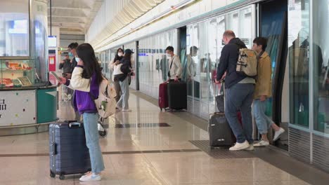 Travelers,-flight-passengers,-and-commuters-exit-a-high-speed-train-as-they-arrive-at-Hong-Kong-international-airport-and-the-departure-hall-terminal