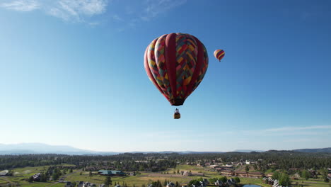 Aerial-View,-Hot-Air-Balloons-Flying-Under-Clear-Blue-Sky-Above-Green-Landscape