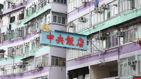 A-restaurant-neon-sign-hangs-from-a-facade-of-a-colorful-residential-building-in-Hong-Kong