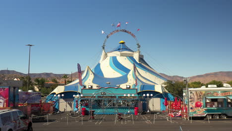 A-traveling-circus-tent-at-the-Antelope-Valley-Mall-in-Palmdale,-California---aerial-pull-back-reveal