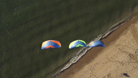 Kitesurfers-lying-on-the-sand-with-kites-raised-in-the-wind,-on-the-coast-of-Tweede-Maasvlakte,-The-Netherlands