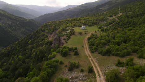 Aerial-approaching-a-solitary-RV,-view-of-mountain-range-of-Tomorr,-Albania