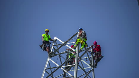 Time-lapse-shot-of-industrial-construction-workers-build-electricity-pole-during-sunny-day-against-blue-sky