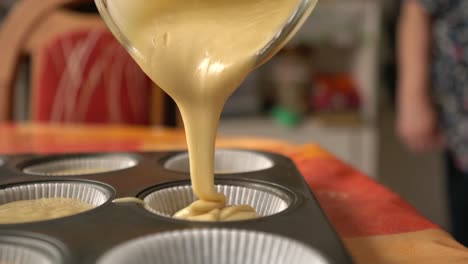 Filling-paper-muffin-cups-with-batter,-cozy-home-kitchen,-baking-steps-close-up