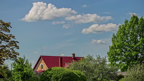 Clouds-rolling,-forming-and-dissipating-in-the-summer-wind-above-a-cottage-in-the-countryside---time-lapse