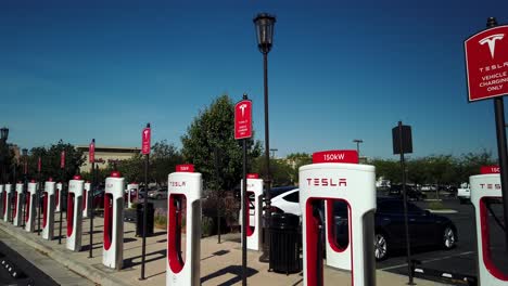 Tesla-Supercharger-Stations,-Row-of-Charging-Stations-for-Electric-Vehicles,-Aerial-ascending-view