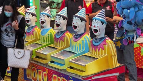 Family-walking-pass-iconic-carnival-games,-laughing-clowns-turning-its-head-from-left-to-right-and-right-to-left-at-Ekka-Brisbane-Royal-Queensland-Show,-Australia