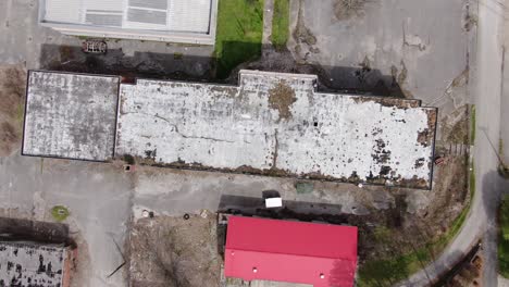 Von-Oben-Nach-Unten-Rotierende-Drohnenaufnahmen-Eines-Großen-Verlassenen-Gebäudes-Mit-Einem-Verfallenden,-überwucherten-Dach