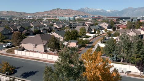 Suburban-neighborhood-nestled-below-the-Wasatch-Front-Rocky-Mountains-in-Lehi,-Utah---pull-back-aerial-flyover