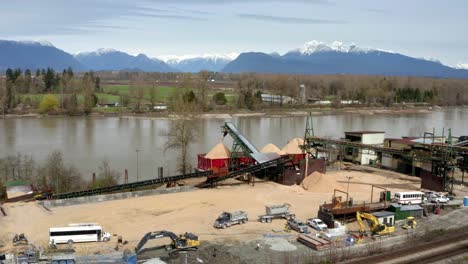 Trucks-And-Loaders-Working-In-The-Industrial-Area-With-Radial-Stacker-Loading-Barge-In-The-Fraser-River