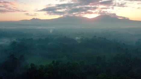 Gleitende-Drohnenaufnahme-Des-Berühmten-Borobudur-Tempels-Bei-Sonnenaufgang-Am-Morgen-Bei-Leicht-Nebligem-Wetter-Und-Bewölktem-Himmel---Magelang,-Indonesien