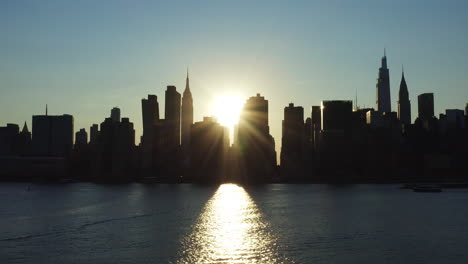 Bright-tilt-up-at-the-East-River-looking-at-the-rare-Manhattanhenge-phenomenon-and-it’s-intense-sunbeam-through-the-buildings