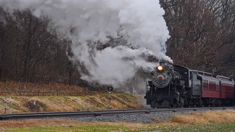 A-View-of-a-Restored-Antique-Steam-Passenger-Train-Approaching,-Blowing-Lots-of-Smoke-and-Steam-on-a-Winter-Day