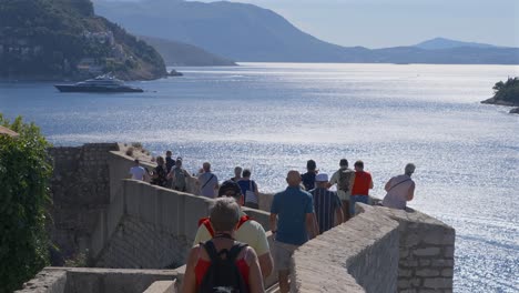 Turistas-Caminando-Por-La-Parte-Superior-De-Las-Murallas-Del-Casco-Antiguo-De-Dubrovnik,-Croacia