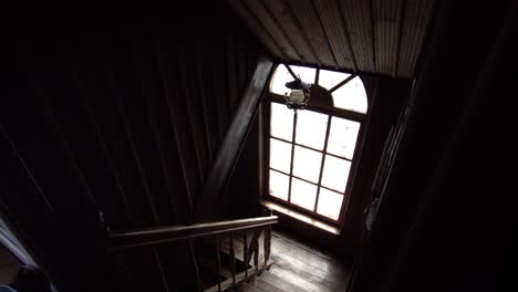 Old-wooden-building-reveals-the-staircase-and-large-arched-window,-Gimbal-shot