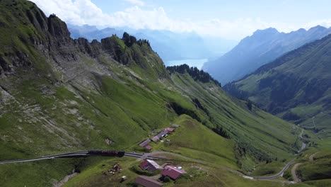 Ein-Zug-Auf-Gleisen-Mitten-In-Den-Bergen-Der-Schweiz,-Der-An-Einem-Klaren,-Blauen-Tag-Vom-Brienzer-Rothorn-In-Die-Atemberaubende-Umgebung-Der-Berge-Der-Alpen-Europas-Hinunterfährt---Der-Brienzersee