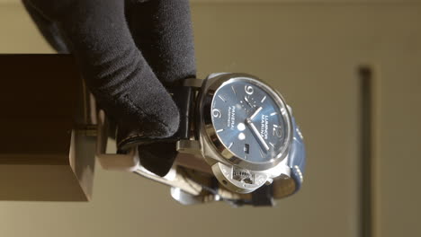 Vertical-Of-A-Person's-Hand-Wearing-Black-Gloves-Carefully-Take-Panerai-Swiss-Watch-Inside-The-Glass-Counter