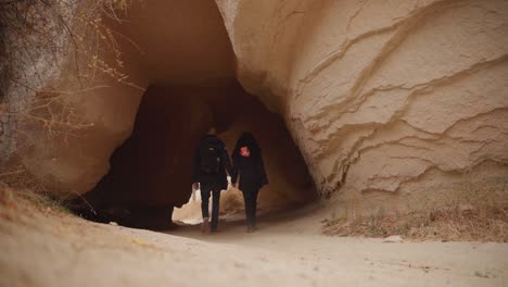 Couple-Walking-Through-Cavern-Pathways-Exploring-Cappadocia-Landscape-In-Turkey