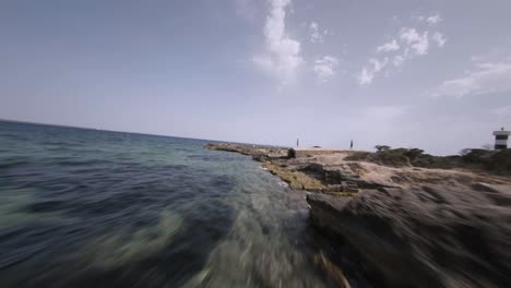 FPV-drone-shot-over-rocky-shoreline-beside-punta-plana-lighthouse-in-Faro-de-s'Estalella,-Mallorca,-Balearic-Islands,-Spain