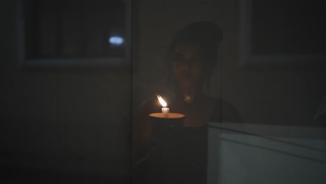 Close-up-of-a-woman's-hands-lighting-a-candle-with-a-match-on-the-dark-background