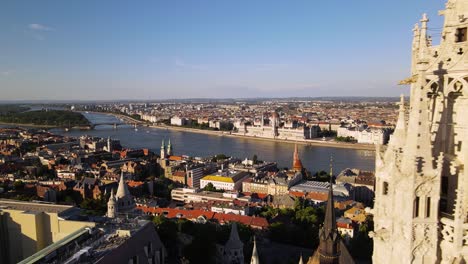 Drone-flying-close-the-bell-tower-of-Matthias-church,-revealing-amazing-panorama-of-iconic-buildings-on-Danube-riverside-in-Pest