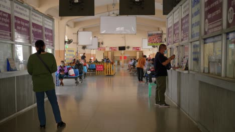 Pasajeros-En-La-Concurrida-Terminal-De-La-Estación-De-Autobuses-Comprando-Boletos-En-El-Mostrador,-Tailandia