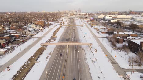 Aerial-forwarding-shot-of-a-busy-highway-going-through-a-urban-city-during-a-nice-winter-day
