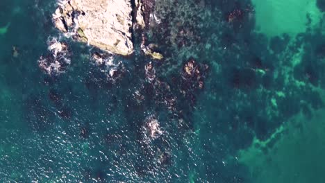 Birdseye-view-from-open-ocean-to-rocky-coast-line-and-seacliffs-to-desert-land