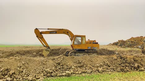A-panning-shot-of-an-excavator-destroying-fertile-soil,-a-striking-contrast-between-the-destruction-of-land-and-the-drought-that-worsens-due-to-it
