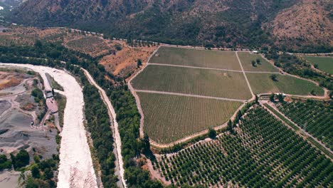 Aerial-shot-of-a-small-river-supplying-the-large-healthy-vineyards-in-Maipo-Canyon,-Chile