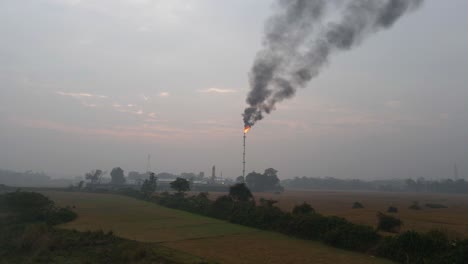 Volando-Hacia-Una-Refinería-De-Petróleo-Con-Una-Chimenea-En-Llamas-Y-Humo-Negro-Contaminando-Las-Tierras-De-Cultivo-A-Su-Alrededor-En-Bangladesh
