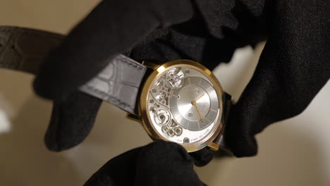 Vertical-Shot-Of-Hands-In-Black-Gloves-Holding-Ultra-thin-Piaget-Altiplano-Watch-Showcasing-Its-Mechanical-Movement