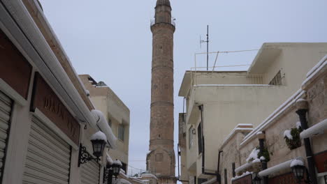 We-see-the-magnificent-minaret-of-the-great-mosque-at-the-back,-among-the-shops-lined-up-left-and-right-in-the-Artuklu-bazaar,-the-old-center-of-Mardin