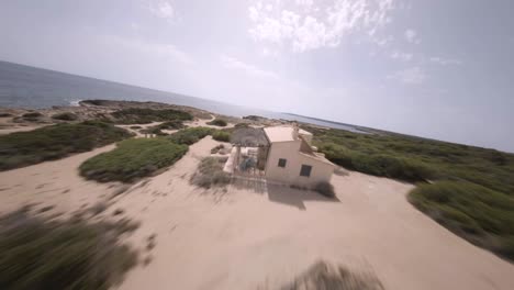 FPV-drone-shot-over-rocky-beaches-covered-with-green-vegetation-in-Faro-de-s'Estalella,-Mallorca,-Balearic-Islands,-Spain-on-a-sunny-day