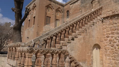 The-camera-sees-the-magnificent-building-of-the-Mor-Behnam-Church,-one-of-the-most-important-church-of-Mardin,-and-the-magnificent-stone-staircase-in-front-of-it,-tilting-it-from-the-bottom-up