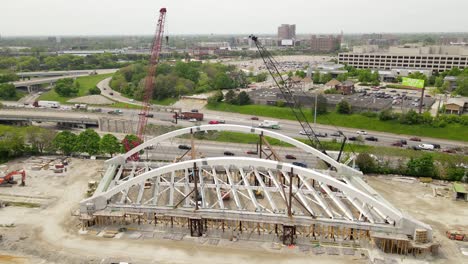 Metal-arch-bridge-construction-for-I-94-freeway-crossing-in-USA,-aerial-side-view