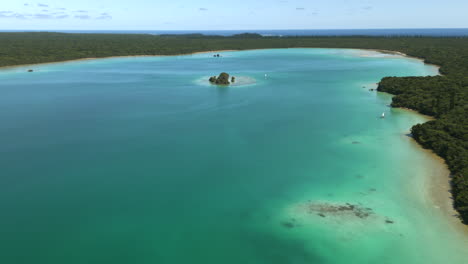 Traditional-pirogues-on-pristine-waters-of-Upi-Bay,-Isle-of-Pines-in-New-Caledonia---pull-back-aerial-reveal