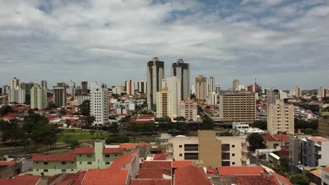 Aerial-rising-through-houses,-tall-residential-buildings-in-background,-Bauru,-Brazil