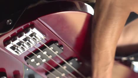 Vertikale-Nahaufnahme-Einer-Männlichen-Hand,-Die-Eine-Rote-E-Bassgitarre-Spielt