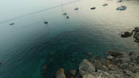 FPV-drone-forward-moving-shot-over-sailboats-docked-along-seaside-in-Cala-d'egos-beach,-Mallorca,-Spain