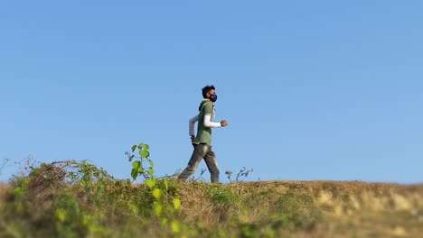 a-young-man-in-a-green-long-sleeve-running-with-a-mask-during-the-pandemic-in-Bangladesh-on-a-sunny,-cloudless-day
