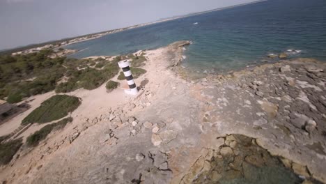 FPV-drone-rotating-shot-over-rocky-shores-alongside-Punta-Plana-lighthouse-in-Faro-de-s'Estalella,-Mallorca,-Balearic-Islands,-Spain-at-daytime