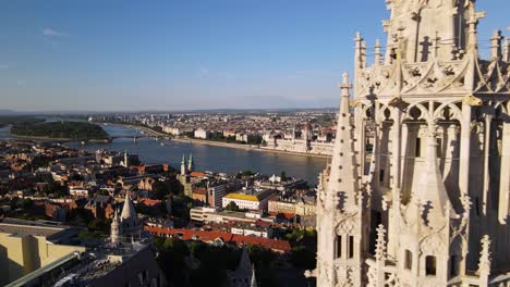 Drone-flying-close-the-bell-tower-of-Matthias-church,-revealing-amazing-panorama-of-iconic-buildings-on-Danube-riverside-in-Pest