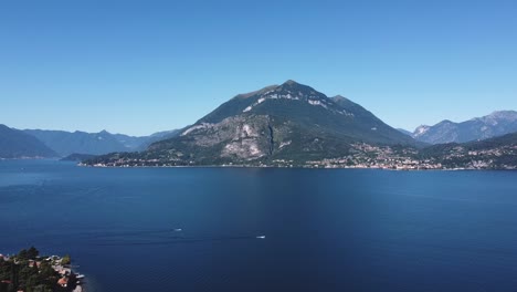 Aerial-wide-shot-showing-beautiful-blue-colored-Lake-Como-with-mountains-in-background-against-blue-sky