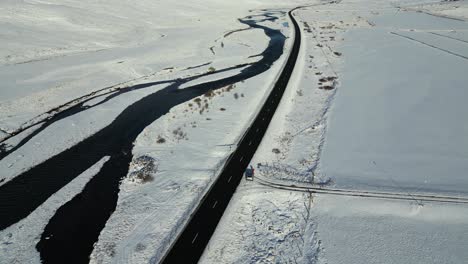 Straße-Am-Fluss-In-Der-Verschneiten-Isländischen-Landschaft---Drohnenflug-Aus-Der-Luft