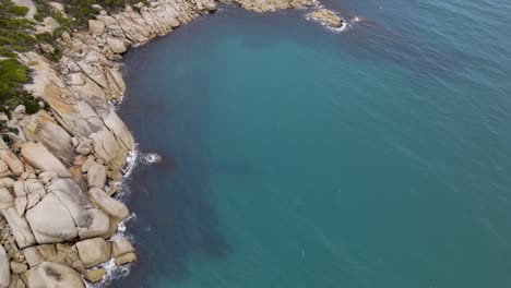 Drone-aerial-rise-up-and-pan-up-over-beautiful-blue-water-and-white-rocks-on-a-sunny-day-in-Wilsons-Promontory