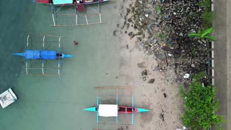 Cinematic,-Top-Down-Birdseye-View-of-Philippine-Bangka-Fishing-Boats-parked-on-pristine-white-sand-beach-shoreline