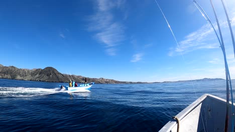 Open-ocean-fishing-boat-traverses-calm-waters,-Bahia-Asuncion-coastline-in-background